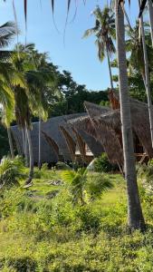 a house with a thatched roof and palm trees at Isla - The Island Experience in El Nido