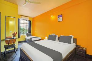 a bedroom with a large bed with an orange wall at Collection O Coorg formerly Hotel Aravind Premier in Madikeri