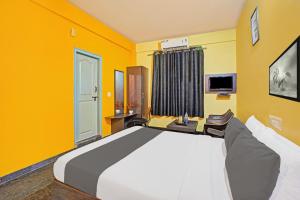 a bedroom with a large bed with yellow walls at Collection O Coorg formerly Hotel Aravind Premier in Madikeri