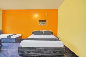 a bedroom with two beds and an orange wall at Collection O Coorg formerly Hotel Aravind Premier in Madikeri