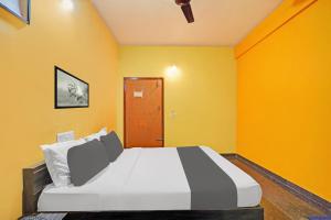 a bedroom with a large bed with yellow walls at Collection O Coorg formerly Hotel Aravind Premier in Madikeri