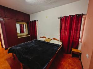 a bedroom with a bed with red curtains at hilldown cottage in Ooty