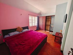 a bedroom with a large bed with a red blanket at hilldown cottage in Ooty