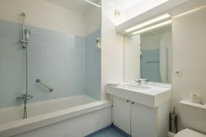 La salle de bains blanche est pourvue d'un lavabo, d'une baignoire et de toilettes. dans l'établissement Residhotel Villa Maupassant, à Cannes