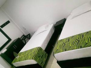 1 Schlafzimmer mit 2 Betten und grüner und weißer Bettwäsche in der Unterkunft Hotel Septima Avenida in Neiva