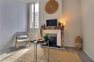 sala de estar con chimenea, TV y silla en Relais 1 - Appartement centre ville, en Bourg-de-Péage