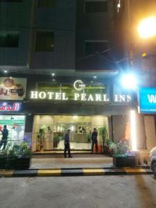 Hotel Pearl Inn في كراتشي: نزل لؤلؤي في الفندق في الليل مع أشخاص يقفون في الخارج