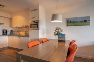 eine Küche und ein Esszimmer mit einem Holztisch und orangefarbenen Stühlen in der Unterkunft Appartementencomplex Juliana 56 in De Koog