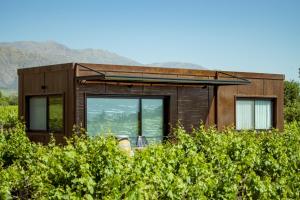 ein winziges Haus auf einem Feld mit Bergen im Hintergrund in der Unterkunft El Porvenir Wine Lodge in Cafayate