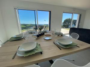 een eettafel met borden en wijnglazen bij Maison neuve vue panoramique sur la mer 6 pers à Crozon in Crozon