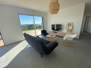 een woonkamer met een zwarte bank en een televisie bij Maison neuve vue panoramique sur la mer 6 pers à Crozon in Crozon