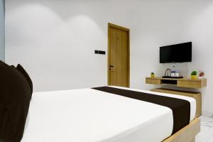 1 dormitorio con 1 cama blanca y TV en Hotel O World View, en Surat