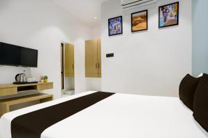 1 dormitorio con 1 cama blanca y TV en Hotel O World View, en Surat