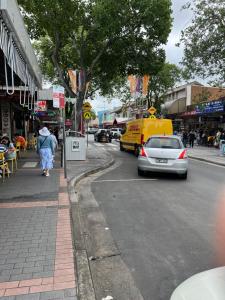 een vrouw die door een straat loopt met een geel busje bij Alison's central apartment in Cabramatta