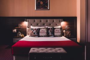 - une chambre avec un grand lit, une couverture rouge et des oreillers dans l'établissement Business Hotel Plovdiv, à Plovdiv