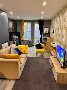 uma sala de estar com um sofá e uma cadeira amarela em Stylish Studio Flat With Private Patio em Bournemouth