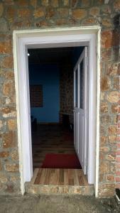 an open door into a brick building with a red rug at AG Cottage Vattakanal in Kodaikānāl