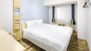 a bedroom with a large white bed and a table at Toyoko Inn Kitakami eki Shinkansen guchi in Kitakami