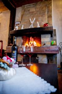 two glasses of wine sitting on a table in front of a fireplace at Velinov Boutique Hotel in Bansko