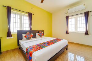 a bedroom with a large bed with yellow walls and windows at FabHotel Saro Sri Residency in Coimbatore