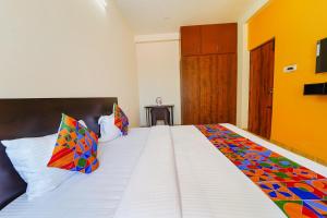 a bedroom with a large white bed with colorful pillows at FabHotel Saro Sri Residency in Coimbatore