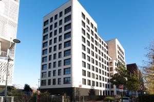 een wit gebouw met ramen aan een stadsstraat bij Résidence Kley Clichy in Clichy