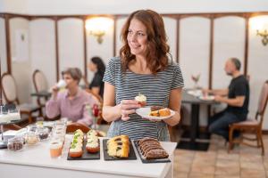 een vrouw met een bord taarten en gebak bij Hotel Litovel in Luhačovice