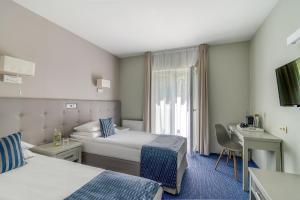 Hotel Aqua Sopot - Destigo Hotels في سوبوت: غرفة فندقية بسريرين ومكتب