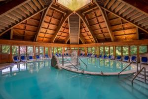 a swimming pool in a wooden building with blue chairs at Ensana Thermal Hévíz in Hévíz