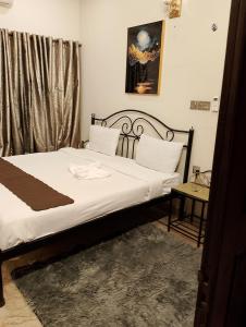 um quarto com uma cama com lençóis brancos e almofadas brancas em Luxury inn Rooms near Expo center , air port , agha khan em Carachi