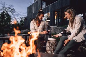 twee vrouwen die rond een vuur voor een gebouw zitten bij KABIN 46 in La Conception