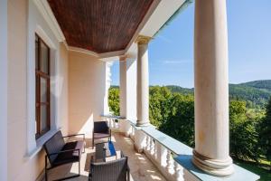 uma varanda com cadeiras e vista para as montanhas em Hotel Château Cihelny em Karlovy Vary