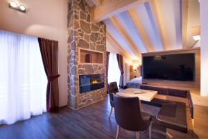 a living room with a stone fireplace and a bedroom at Chalet Marcora in Campitello di Fassa