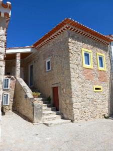 una pequeña casa de piedra con una puerta roja y escaleras en Moradia do castelo, férias tranquilas, en Ourém