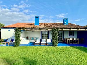 ein Haus mit einer Terrasse mit Stühlen und einem Tisch in der Unterkunft Comporta - Wood & Blue in Comporta