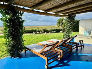 eine Gruppe von Stühlen und Tischen unter einer Pergola in der Unterkunft Comporta - Wood & Blue in Comporta