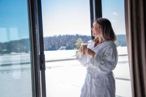 a woman holding a cup of coffee looking out of a window at Estérel Resort in Esterel