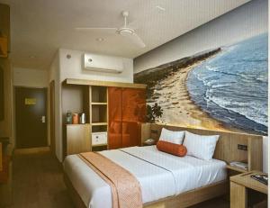 een slaapkamer met een bed en een schilderij van een strand bij Ginger Goa Candolim in Candolim