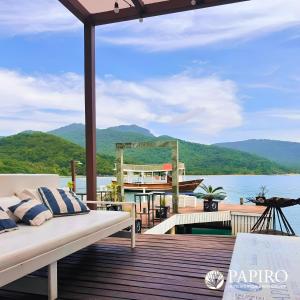 une terrasse avec un lit et un bateau sur l'eau dans l'établissement Pousada Papiro Boutique, à Abraão