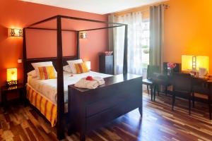 a bedroom with a canopy bed and a desk at Auberge du Manet in Montigny-le-Bretonneux