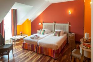 a hotel room with two beds and orange walls at Auberge du Manet in Montigny-le-Bretonneux