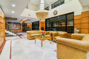 a lobby with couches and a table and a clock at Capital O Grand Plaza in Coimbatore