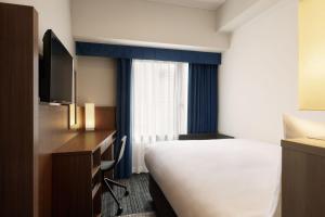 a hotel room with a bed and a desk and a tv at Four Points Flex by Sheraton Osaka Umeda in Osaka