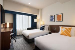 a hotel room with two beds and a desk at Four Points Flex by Sheraton Osaka Umeda in Osaka