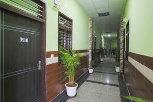 a corridor with potted plants in a hallway at Capital O A-one in Manesar