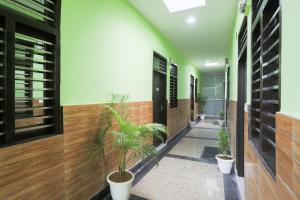 a hallway with potted plants in a building at Capital O A-one in Manesar