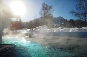 une piscine d'eau avec de la neige et du soleil dans l'établissement Gasthaus Auwirt, à Fieberbrunn