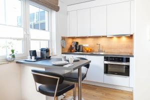 a kitchen with white cabinets and a table with chairs at Simon´s Ferienwohnungen in Kurort Oberwiesenthal