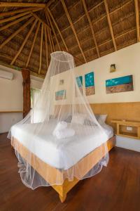 a bed with a mosquito net in a room at Kabañas Ojo de Agua in Puerto Morelos