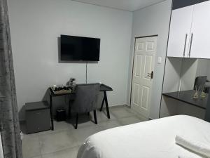 una camera con letto, scrivania e TV di Mountain Drive Apartments a Mbabane